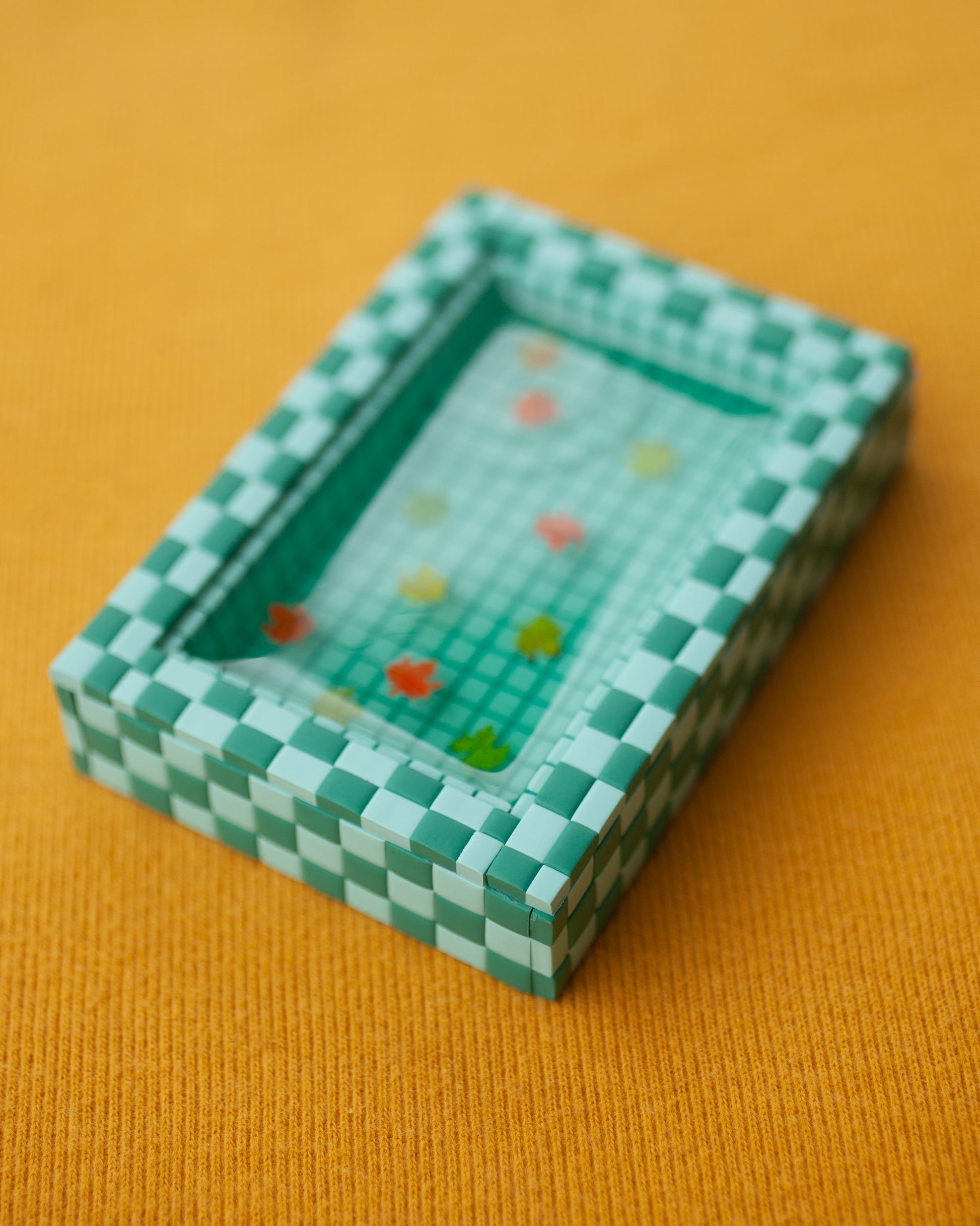 miniature pool with green tiles and fall leaves suspended in the resin water