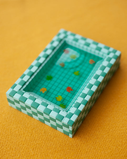 miniature pool with green tiles and fall leaves suspended in the resin water
